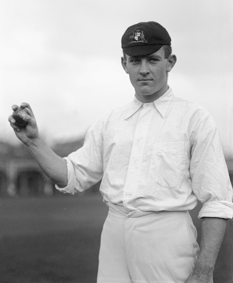 Image 1 of 6 - Black and white photo of a young man in cricket uniform holding up a cricket ball