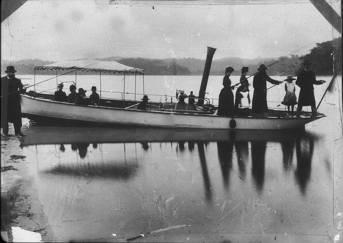 Image 4 of 4 - An aged black and white photo showing a group of people on steamboat which is positioned at the shoreline of a river.