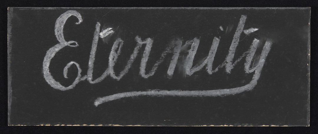 Image 2 of 4 - The word ‘Eternity’ written with white chalk on black cardboard.