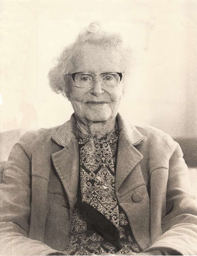 Image 3 of 4 - A black and white portrait photograph of an elderly woman wearing glasses sitting down on a chair