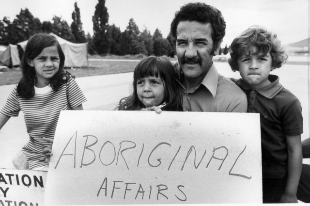 Image 3 of 4 - Black and white image of Charles Perkins and his children protesting outside. They are holding a sign that reads ‘ABORIGINAL AFFAIRS’.