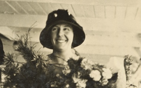 Sepia image of a woman holding flowers wearing a hat