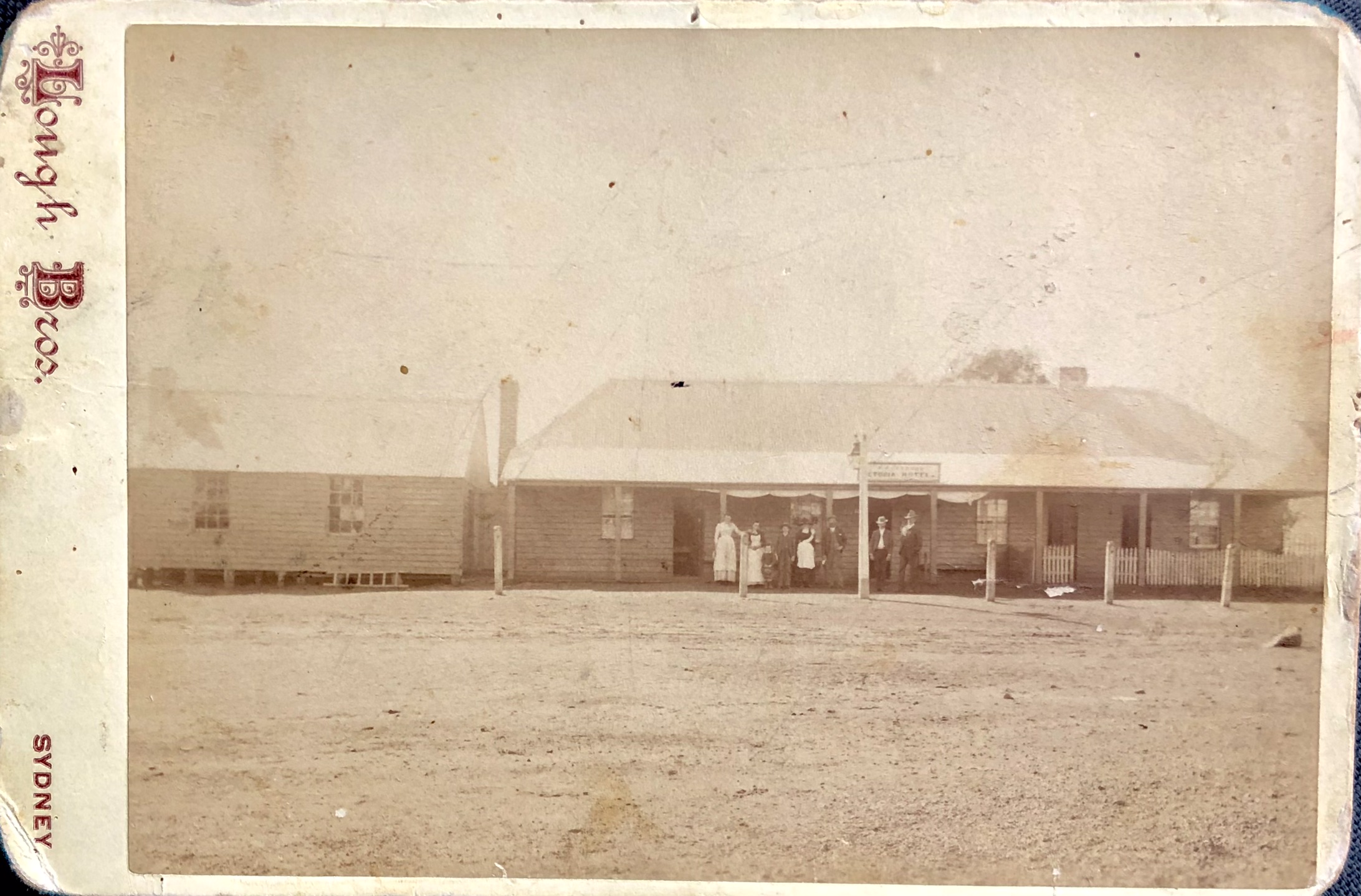 Image 2 of 6 - A photograph of the Victoria Hotel, now known as the Old Vic. A group of seven people are standing under the front verandah looking to the camera