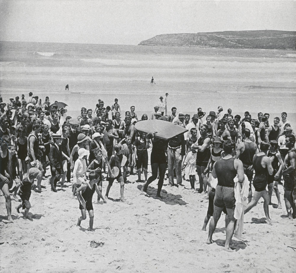 Image 1 of 6 - This 1915 photograph by Frank Bell shows crowds surrounding Duke Kahanamoku at Freshwater Beach.