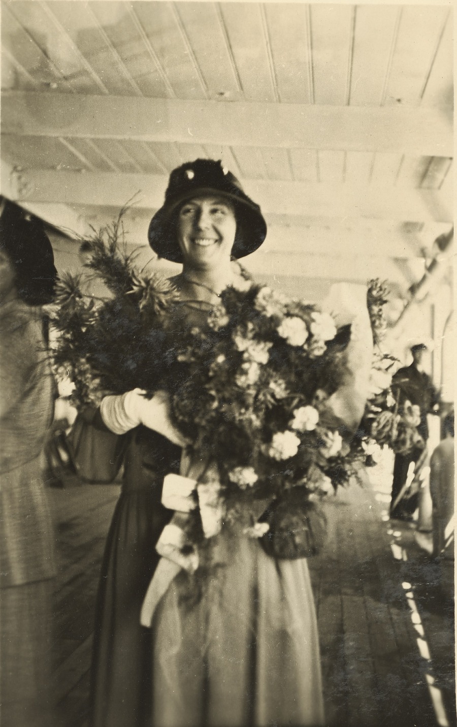 Black and white photograph of a woman wearing a hat holding a bouquet of flowers