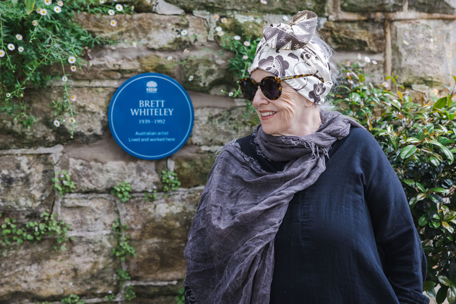 Image 2 of 3 - A photograph of Wendy Whiteley standing alongside Brett Whiteley plaque at her Lavender Bay home
