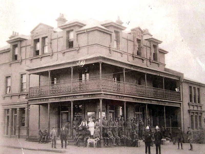 Image 2 of 6 - Black and white image of a three-storey commercial hotel with several people and a dog out the front on the bottom floor. The hotel also has a balcony on the second floor.