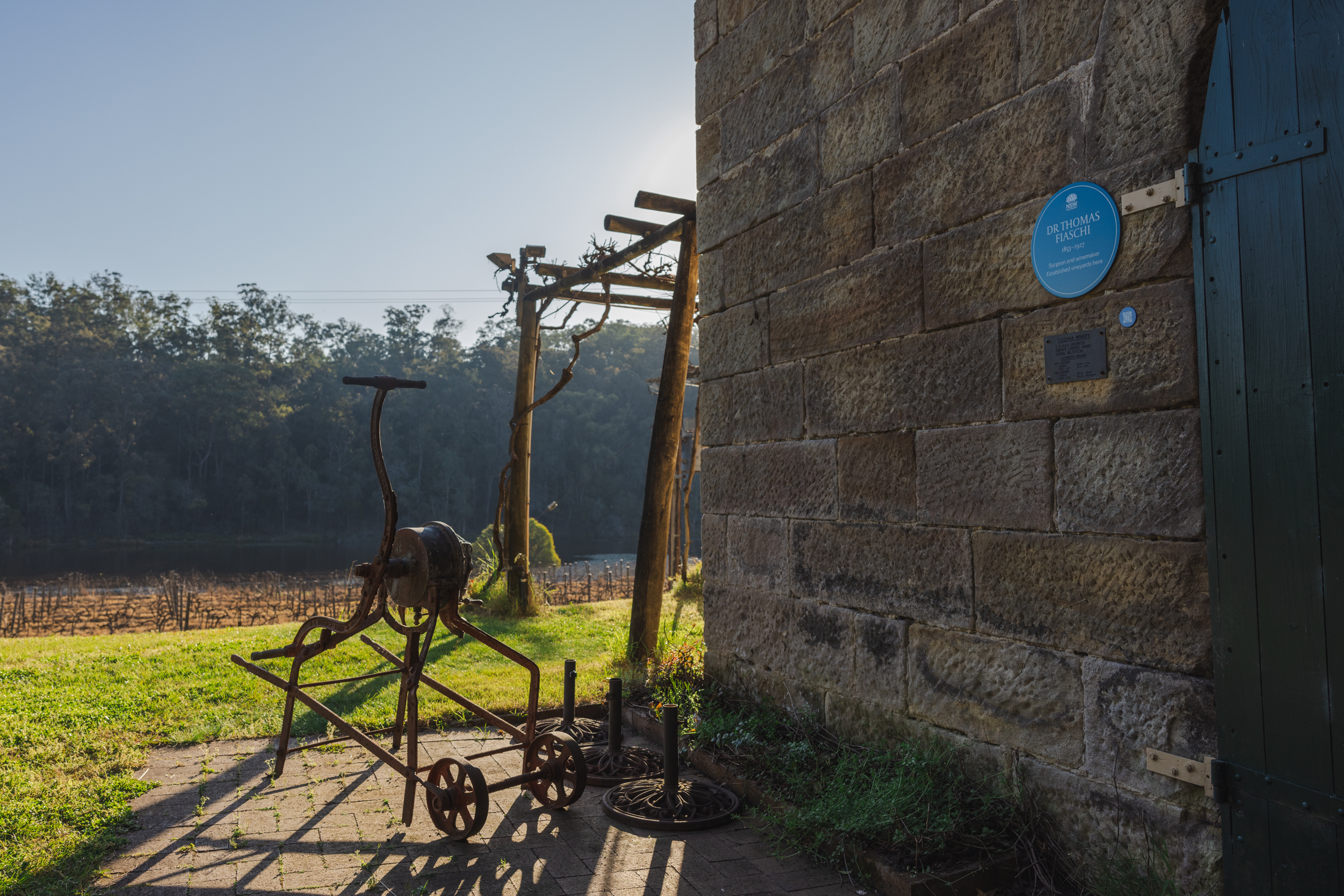 Image 5 of 6 - A picture of a blue plaque on a sandstone building with a vineyard in the background