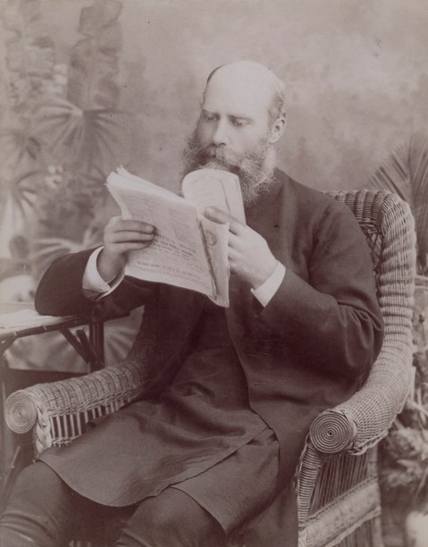 Image 4 of 6 - A formal portrait of Bishop Sydney Linton. He is seated in a cane chair reading some papers